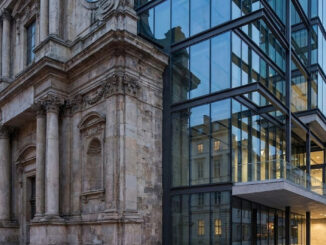 A historic stone building facade seamlessly integrated with a contemporary multi-story glass and steel architectural addition.