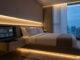 A luxury villa bedroom featuring warm ambient lighting and a bedside touch-screen interface for smart home automation.